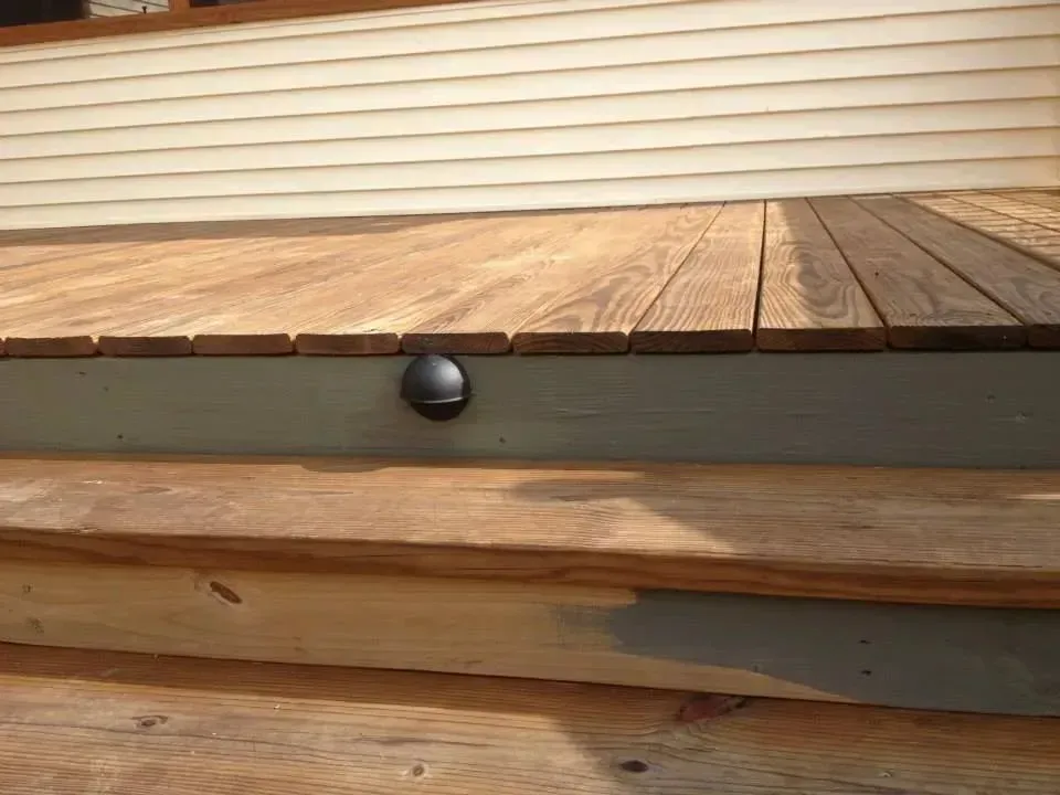 A close up of a wooden deck with stairs leading up to it.