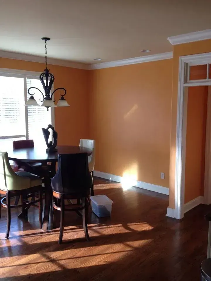 A dining room with orange walls and a table and chairs