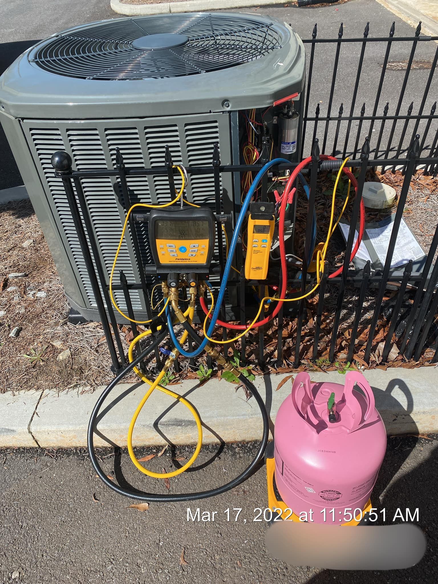A large air conditioner is being repaired on the side of the road.