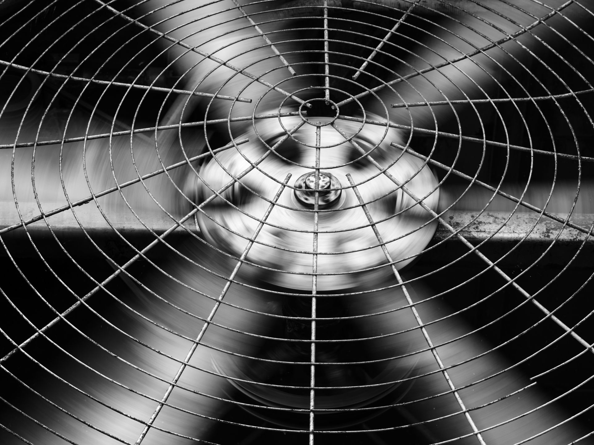 Rotating fan blades behind a metal safety cage.