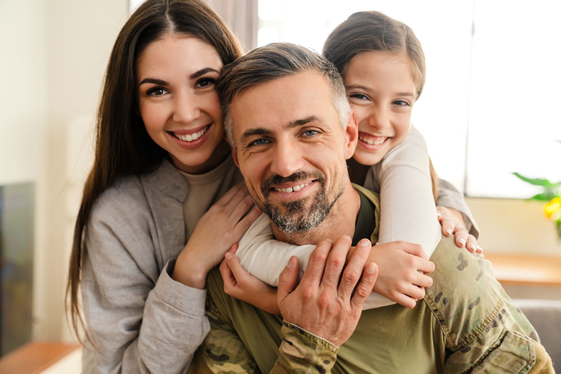 Smiling family hugging on a couch in a bright living room