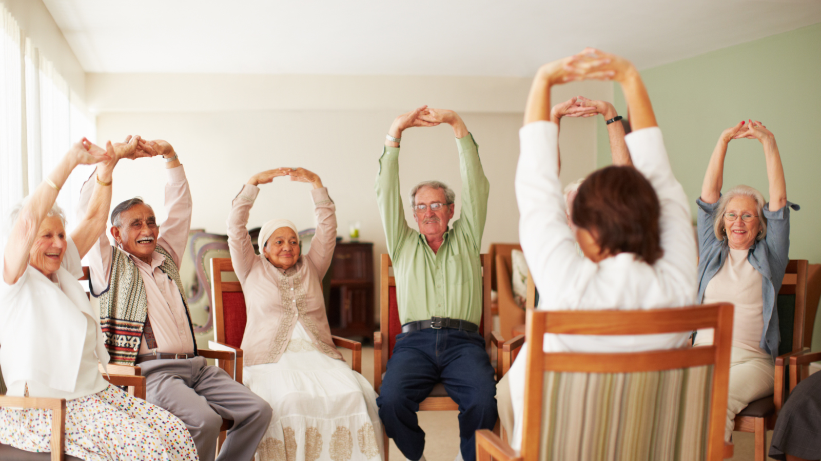Person wearing yellow gloves dusting a circular mirror with a fluffy duster in a bathroom.