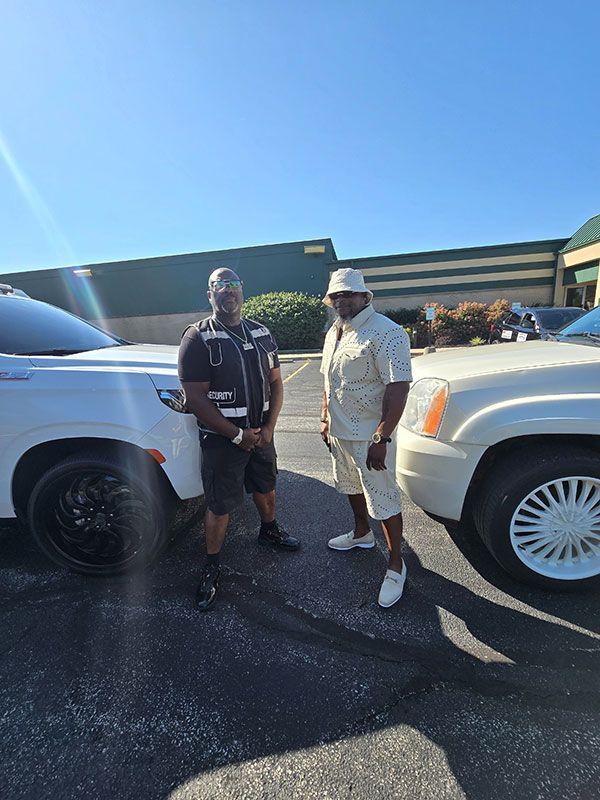 Two men are standing next to a white suv in a parking lot.