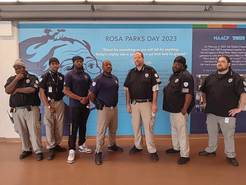 A group of security guards are standing in front of a wall.