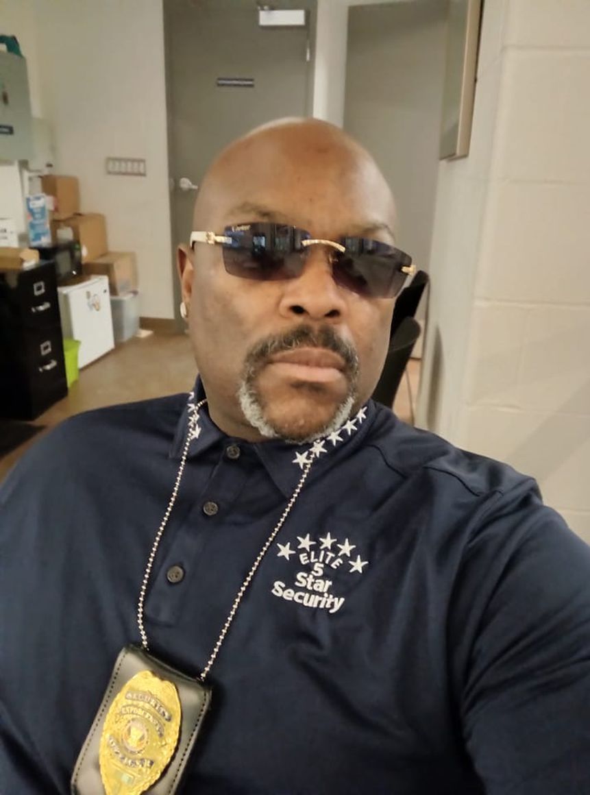 A man wearing sunglasses and a security shirt