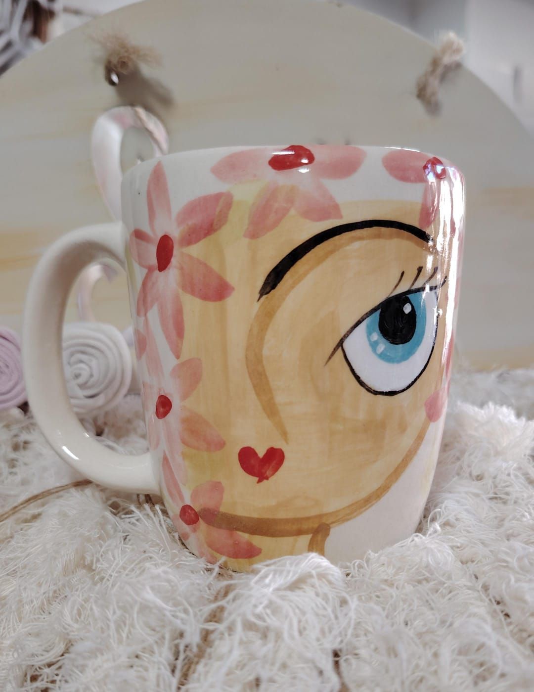 Taza de color crema con rayas verticales verdes, colocada sobre una superficie blanca esponjosa.