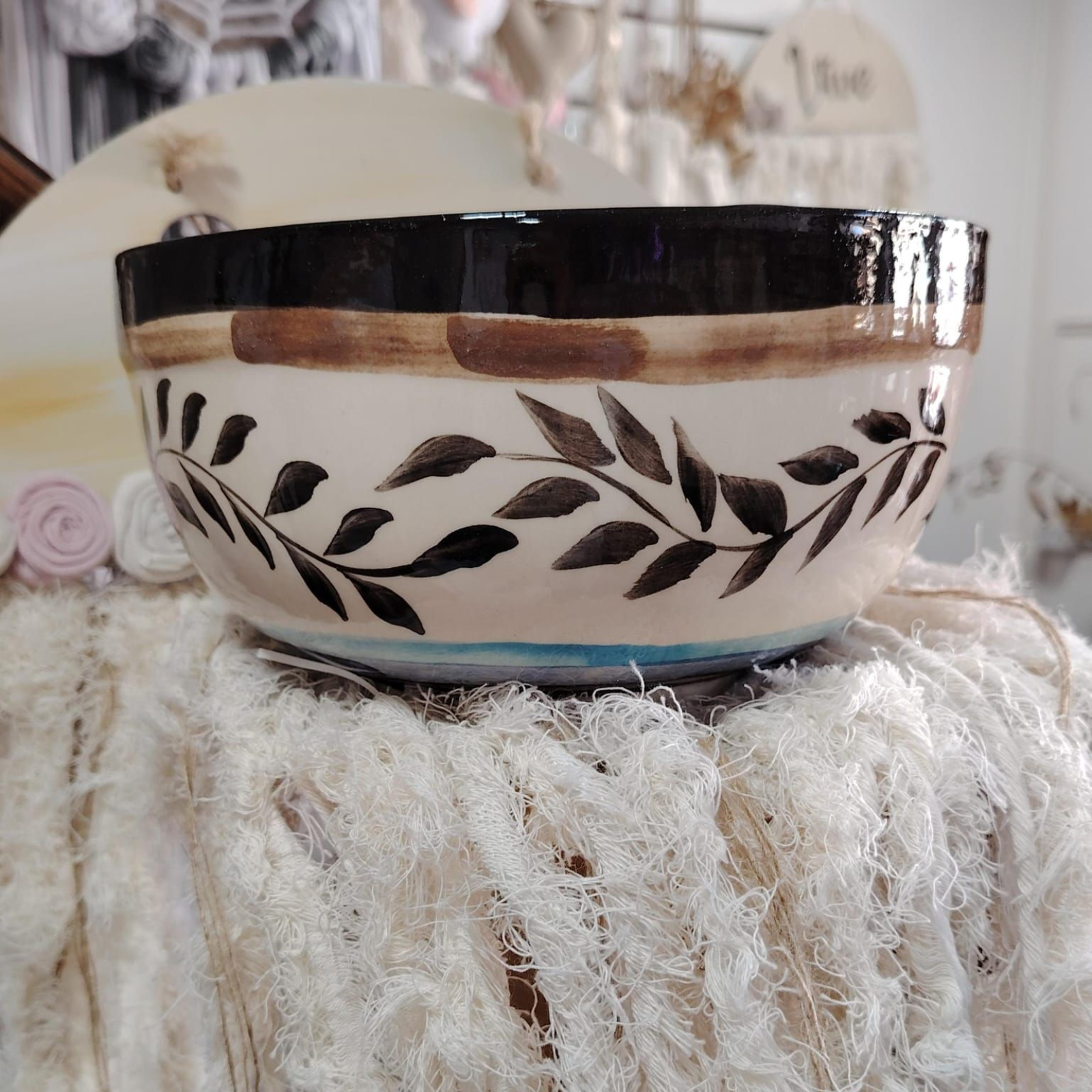 Cuenco de cerámica pintado a mano con margaritas rosas y hojas verdes sobre fondo blanco.