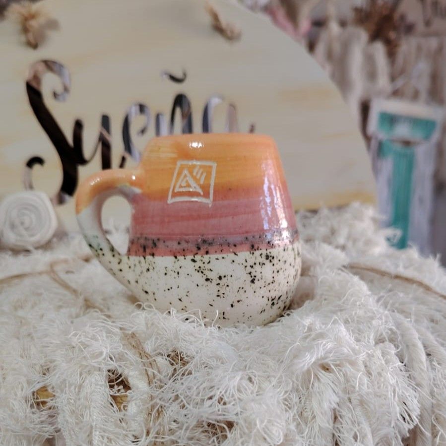 Taza de cerámica colorida sobre tela blanca texturizada, letrero 