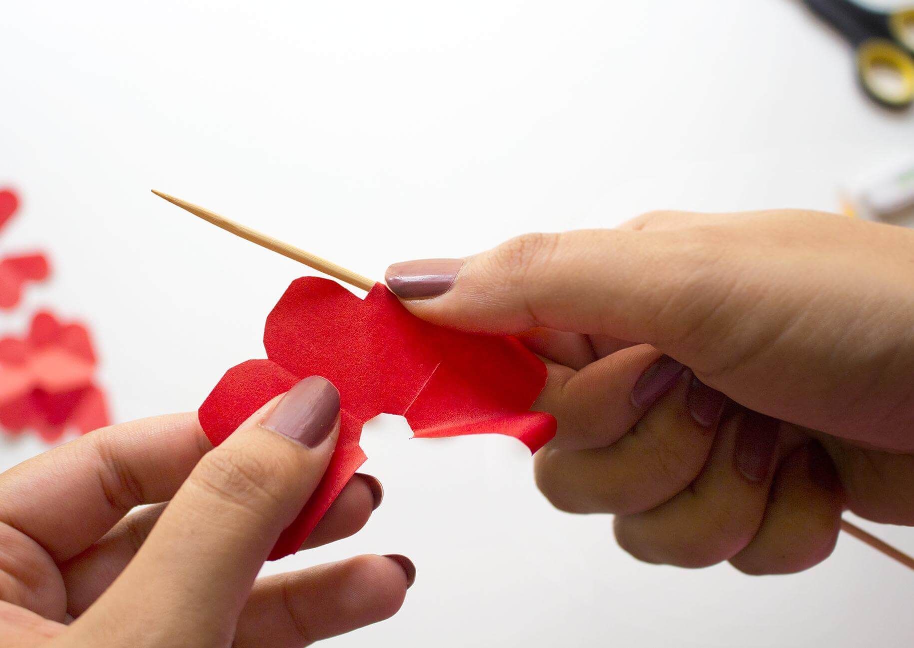 Woman curving paper with a wooden skewer