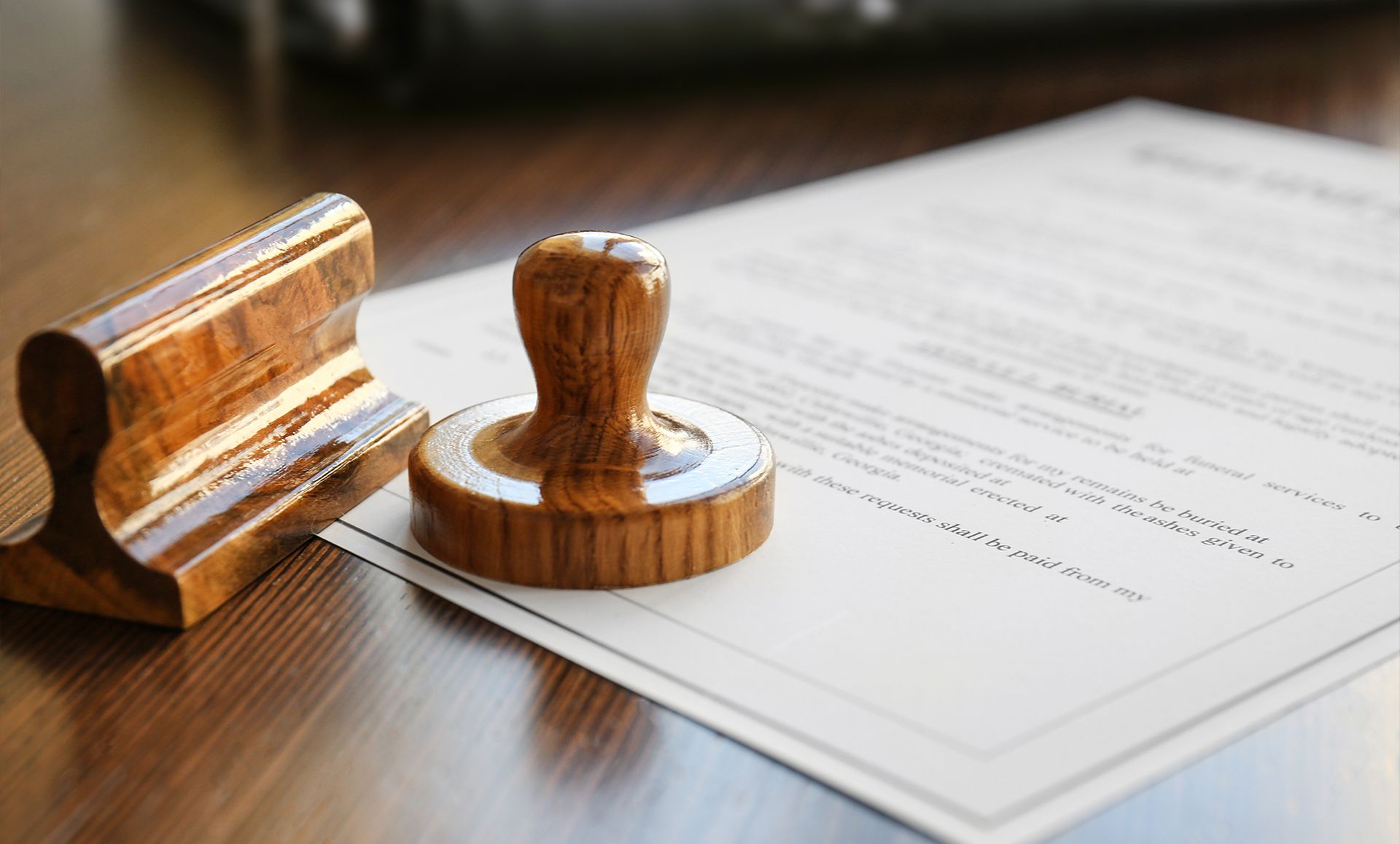 Wooden stamp and its base next to a document on a wooden table.