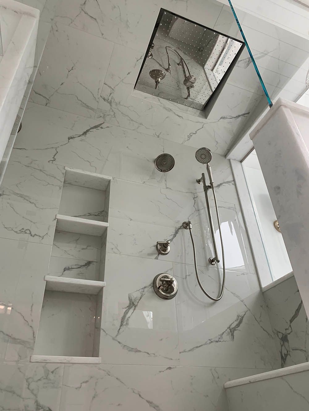 A bathroom with a shower and a mirror on the wall.