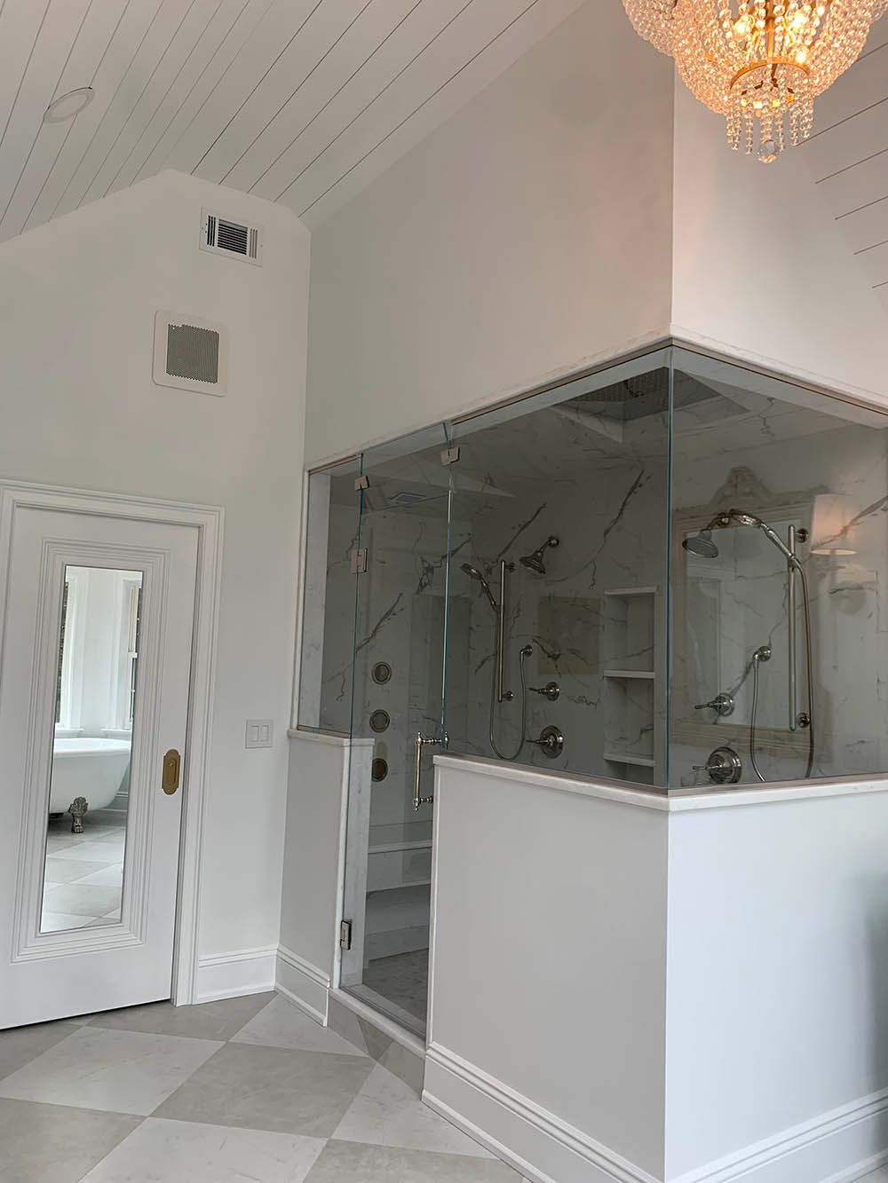 A bathroom with a walk in shower and a chandelier hanging from the ceiling.
