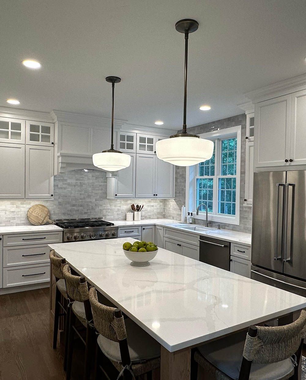 A kitchen with white cabinets , stainless steel appliances , a large table and chairs.