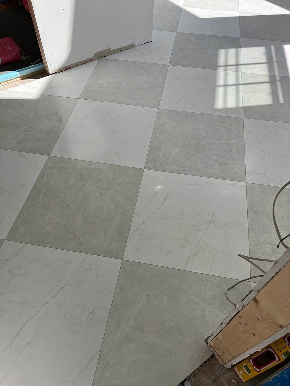 A checkered tile floor is being installed in a room.