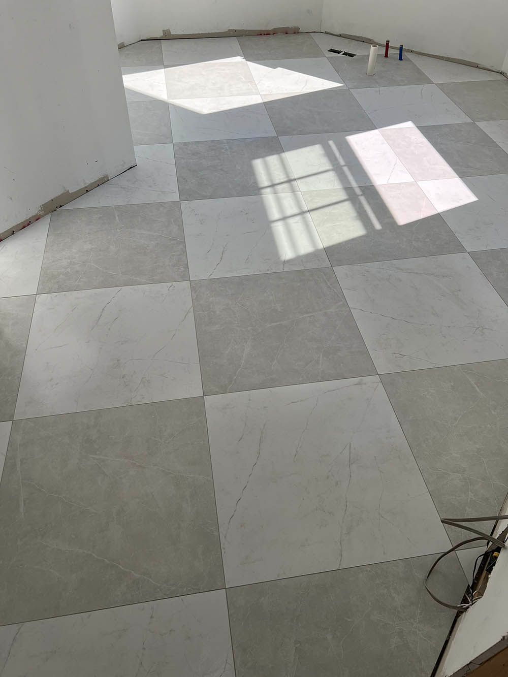A room with a checkered tile floor and a window.
