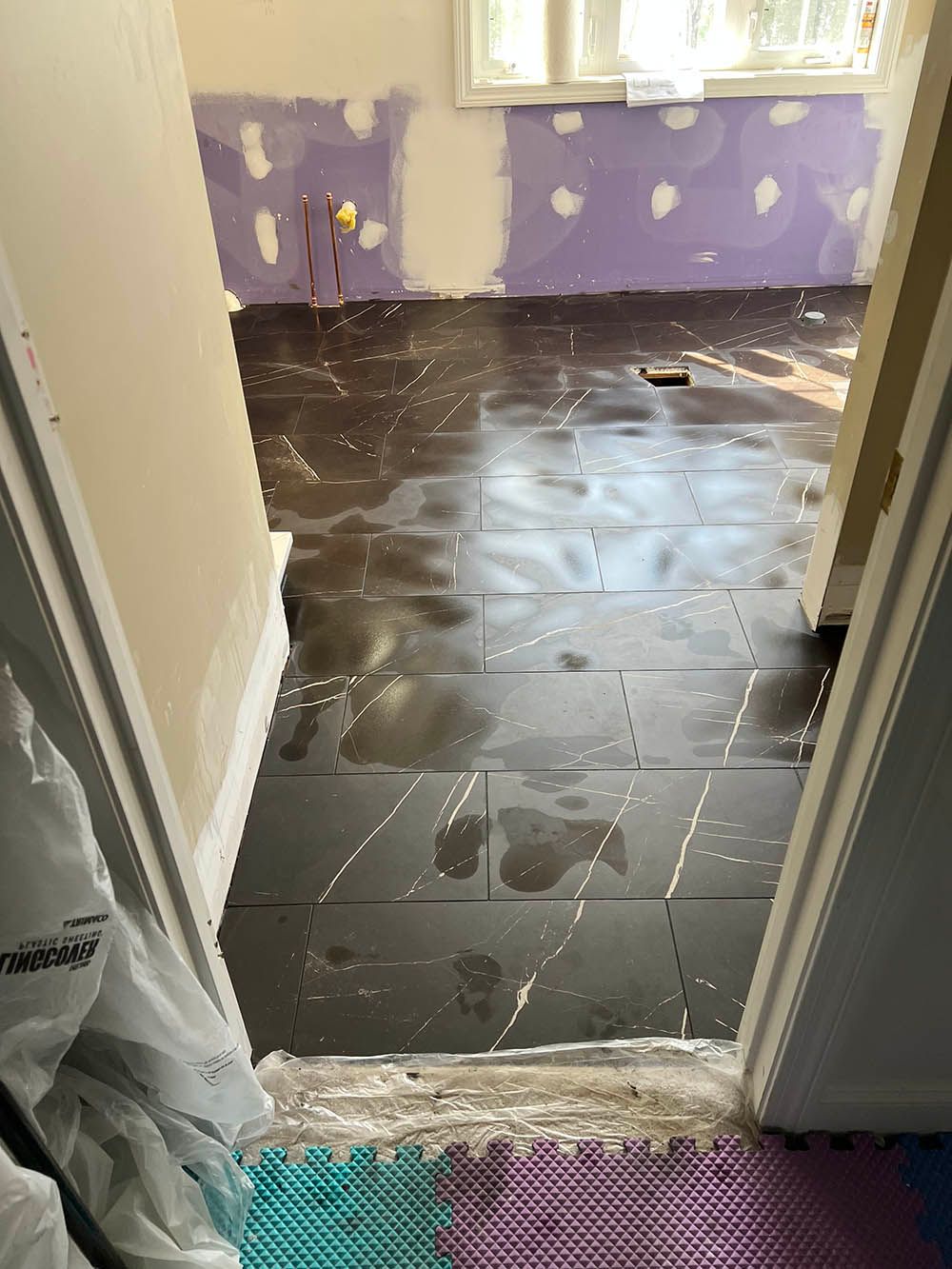 A room with a purple wall and a black tile floor.