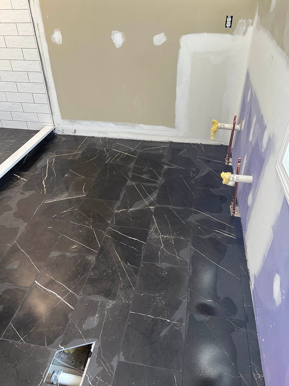 A bathroom with a black tile floor and a purple wall.