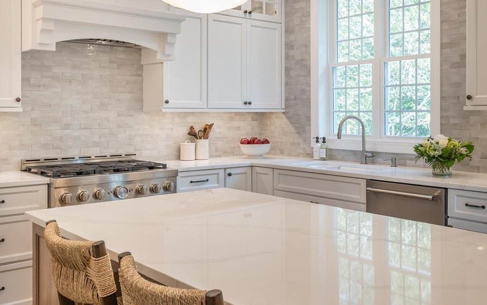 A kitchen with white cabinets , a stove , a sink , and a large island.