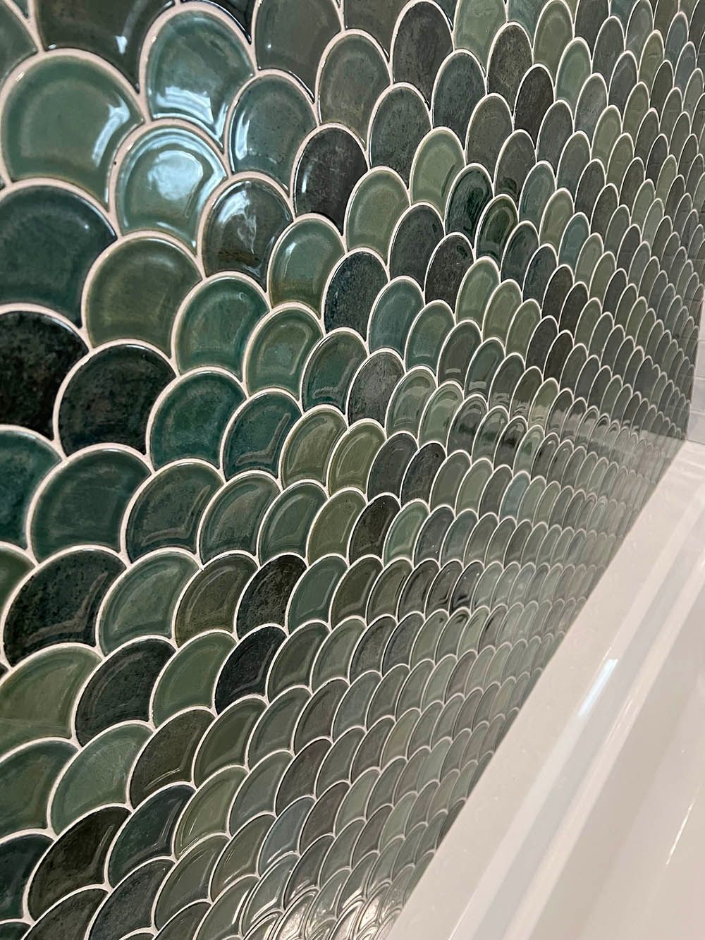 A close up of a wall with green tiles that look like fish scales.