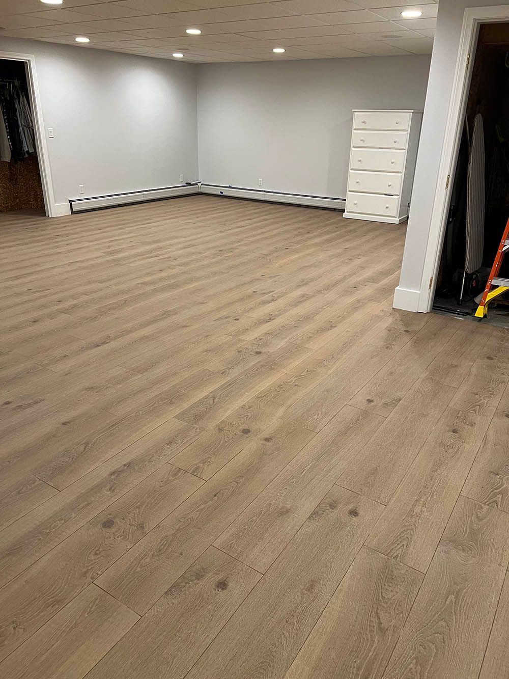 A large empty room with hardwood floors and white walls.