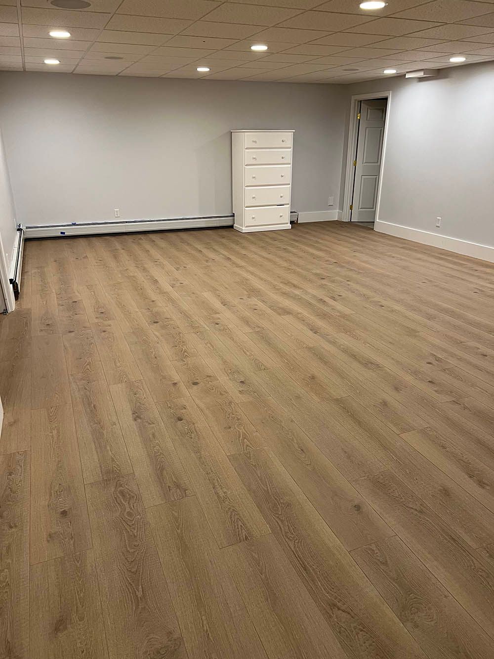 A large empty room with wooden floors and white walls.
