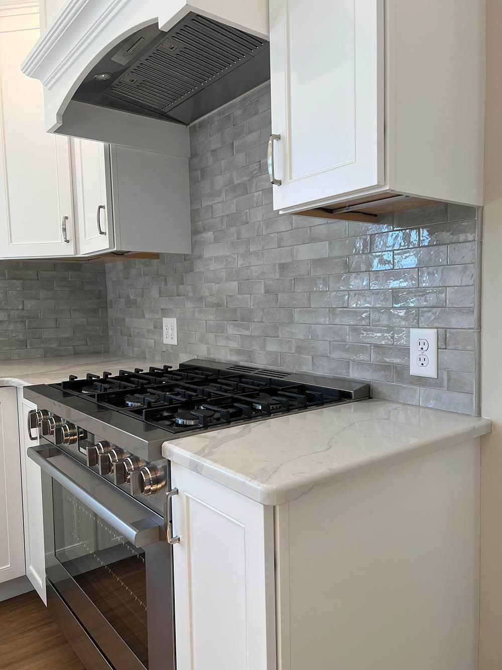 A kitchen with a stove top oven and white cabinets.