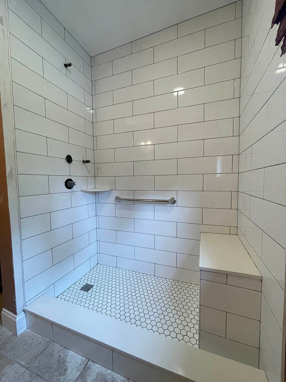 A bathroom with white tiles and a walk in shower.