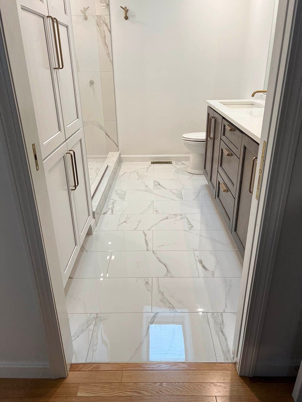 A bathroom with a walk in shower , sink , and cabinets.