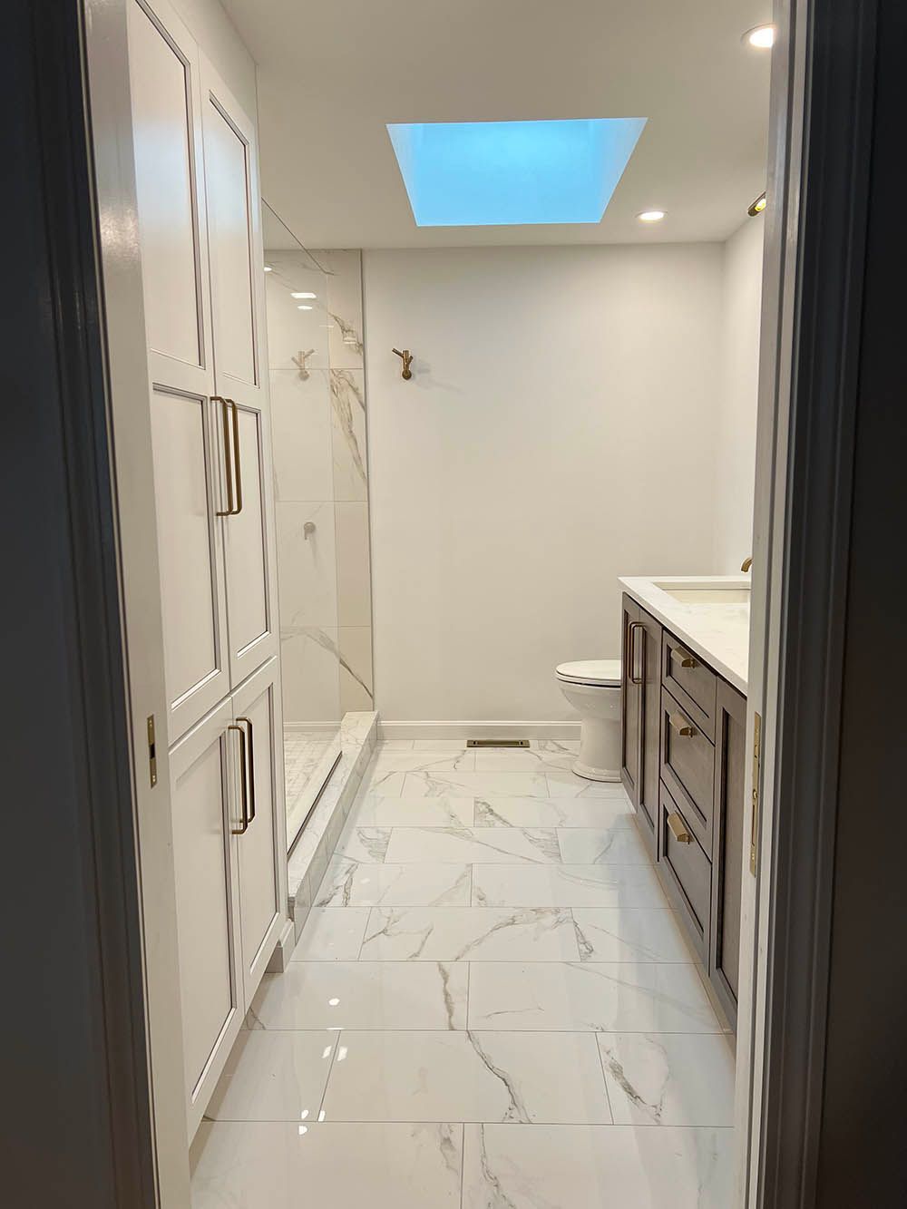 A bathroom with a skylight in the ceiling and a walk in shower.