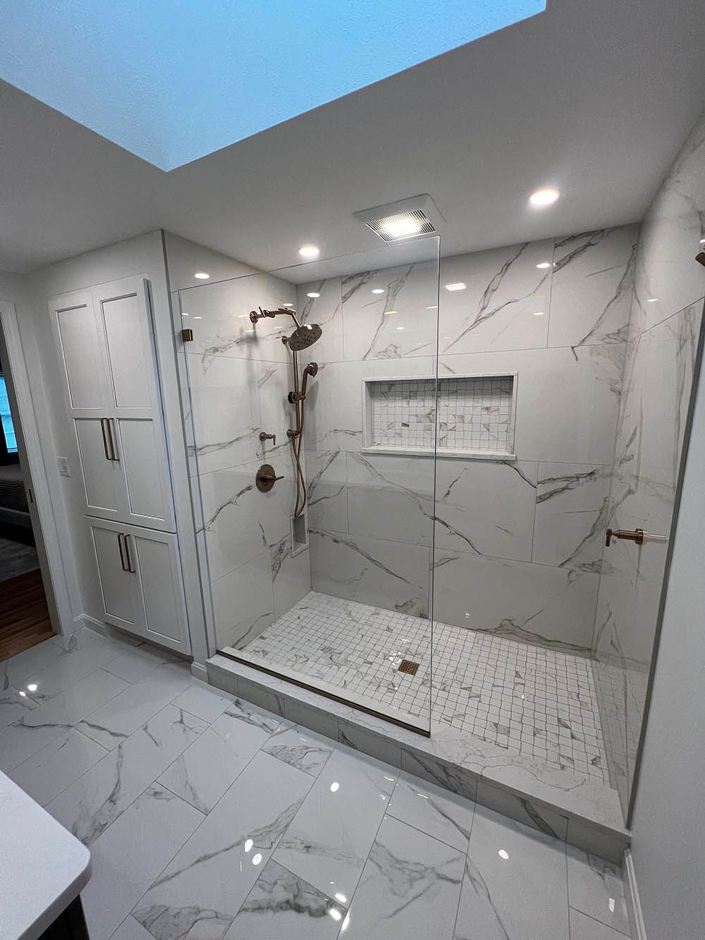 A bathroom with a walk in shower and a skylight.