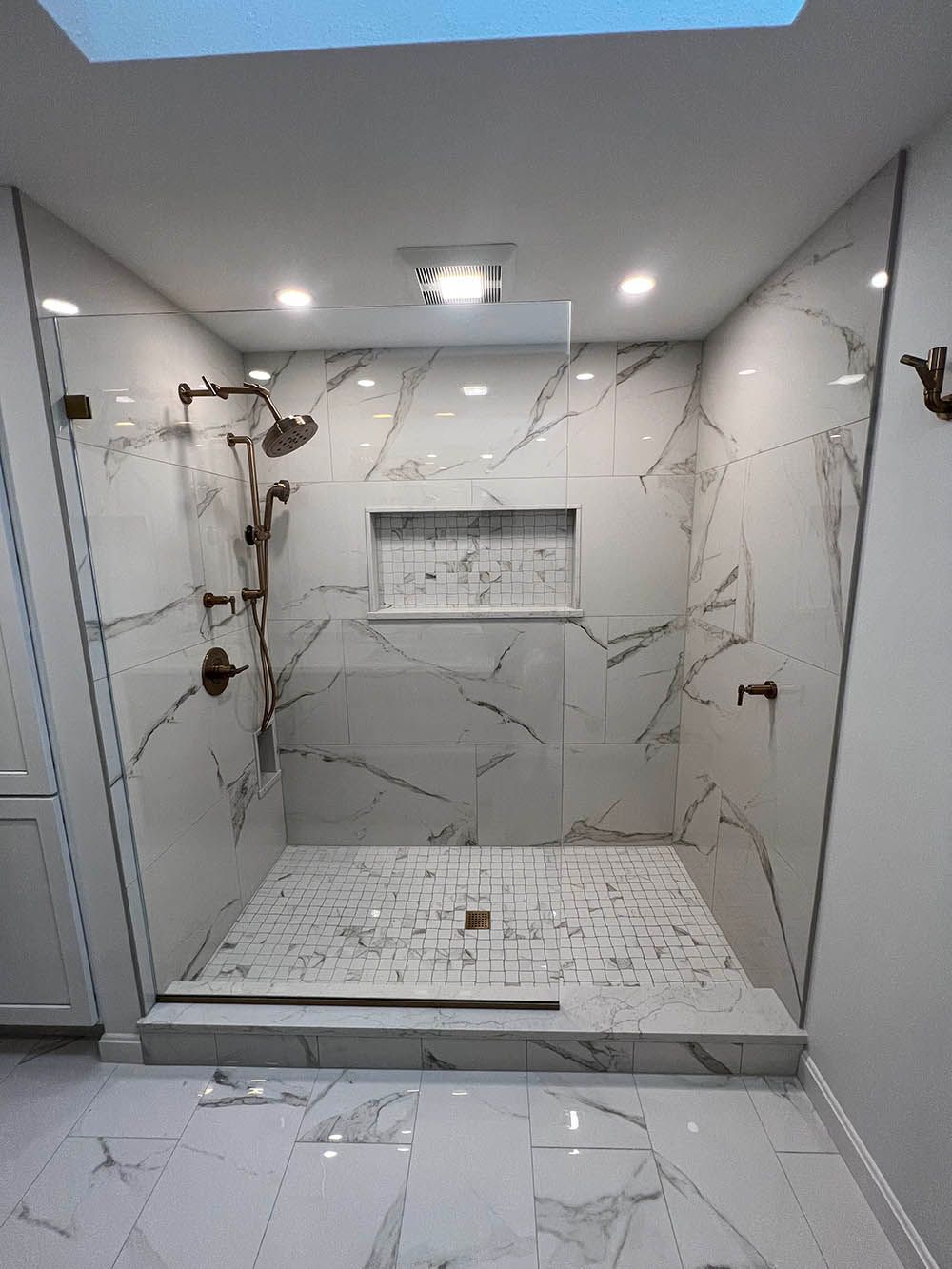 A bathroom with a walk in shower and a skylight.