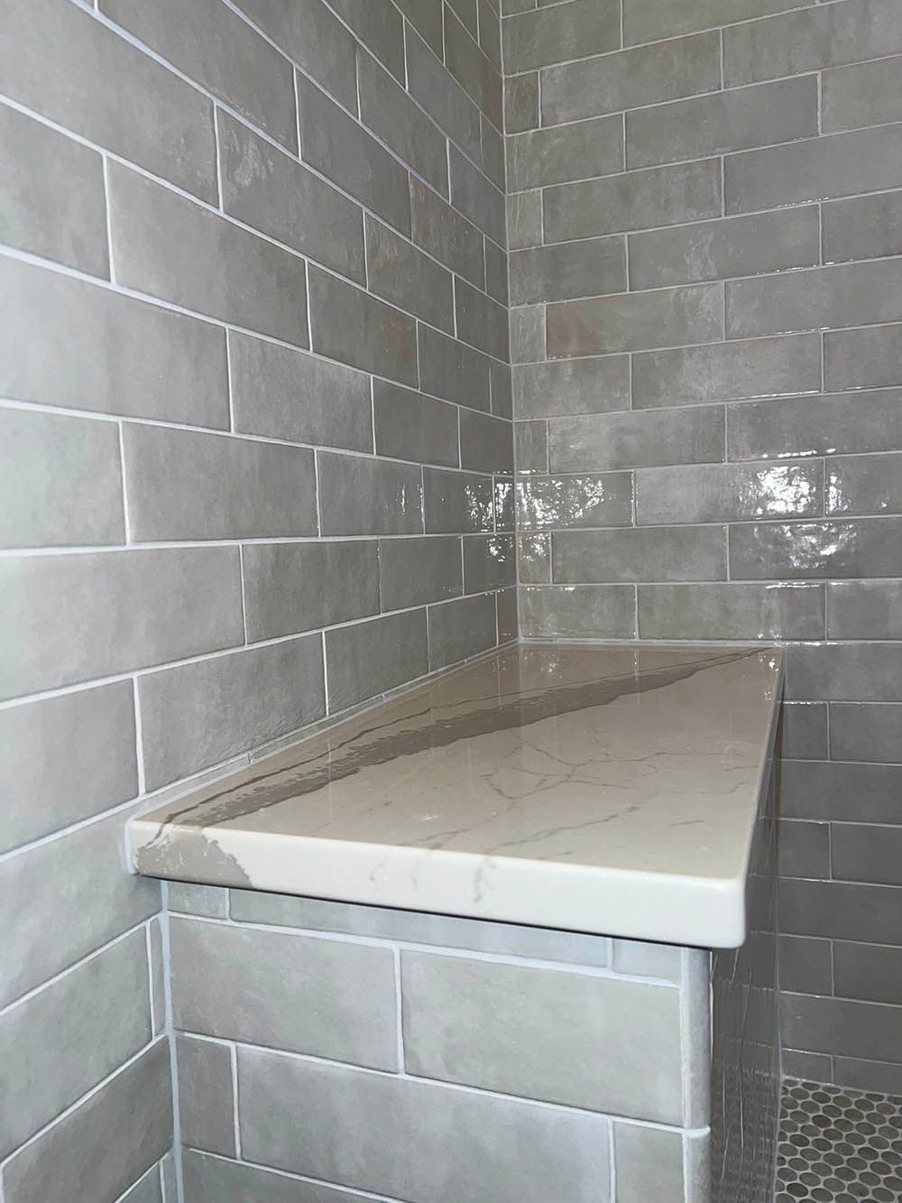 A bathroom with gray tiles and a white counter top.
