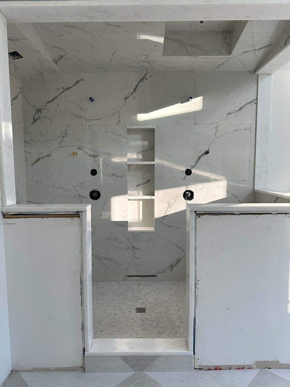 A bathroom with marble tiles and a walk in shower.