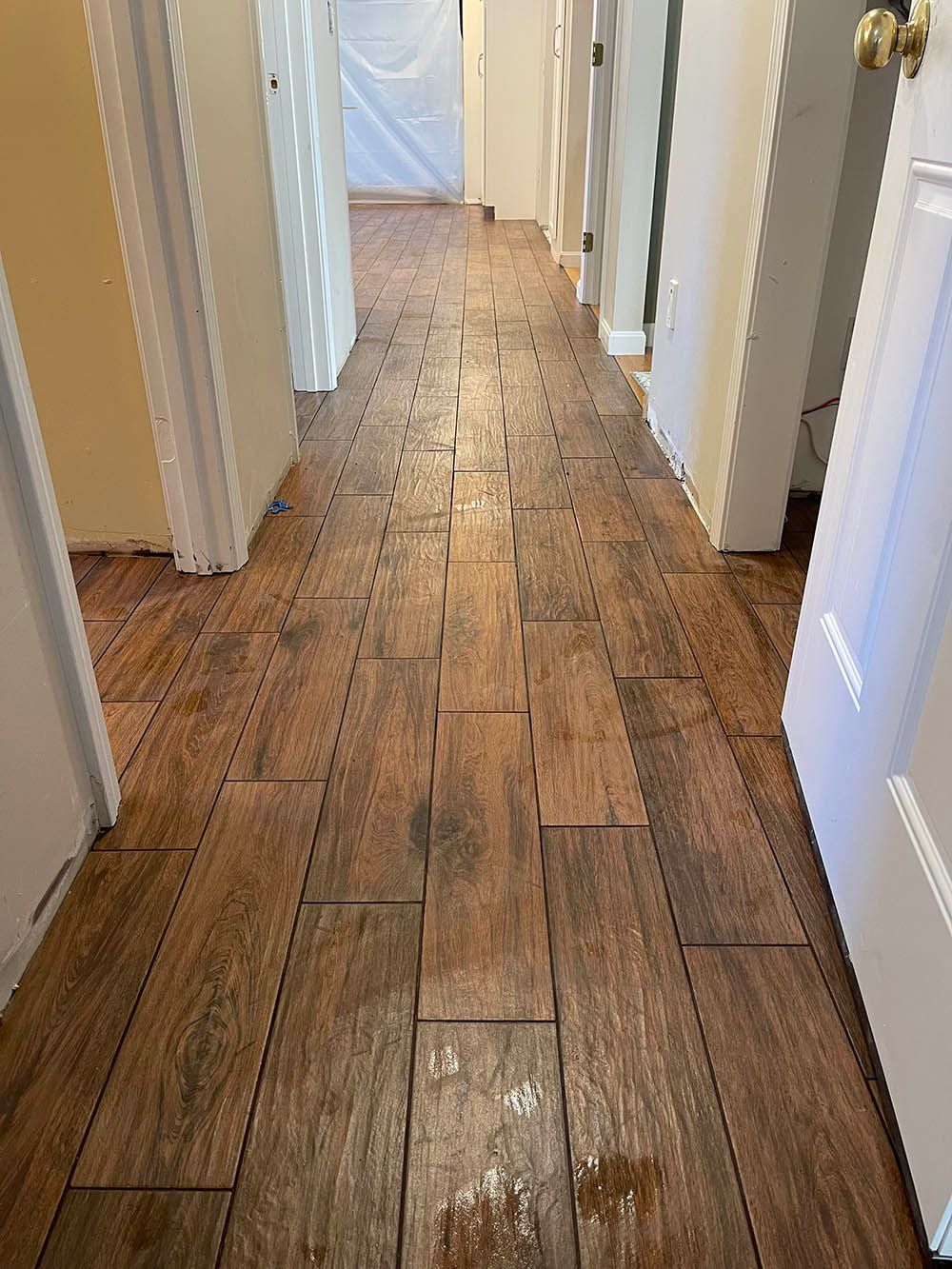 A hallway with a wooden floor and a lot of doors.