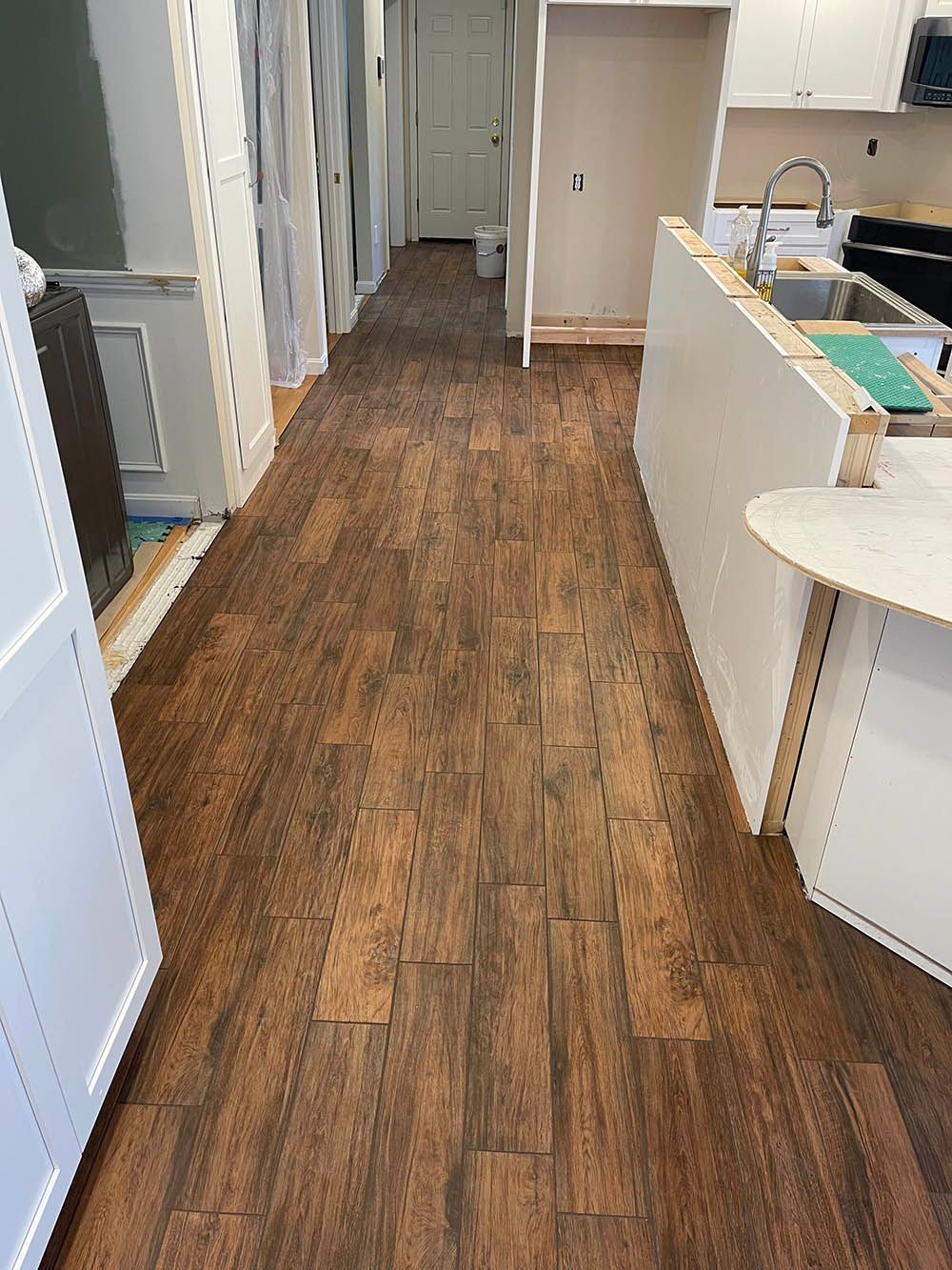 A long hallway leading to a kitchen with wooden floors.