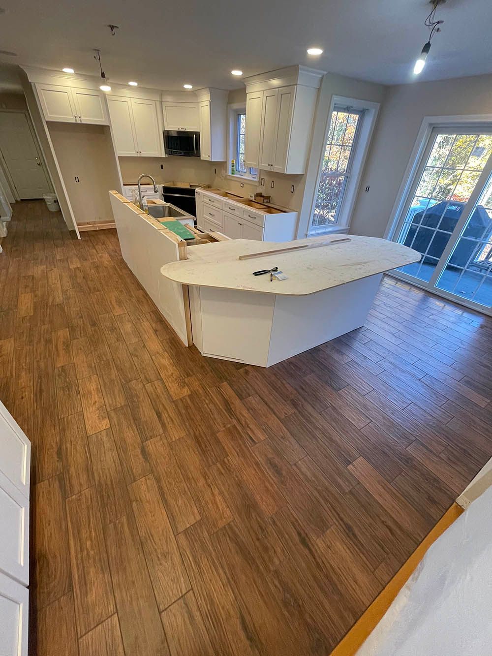 A kitchen with wooden floors and white cabinets is being remodeled.
