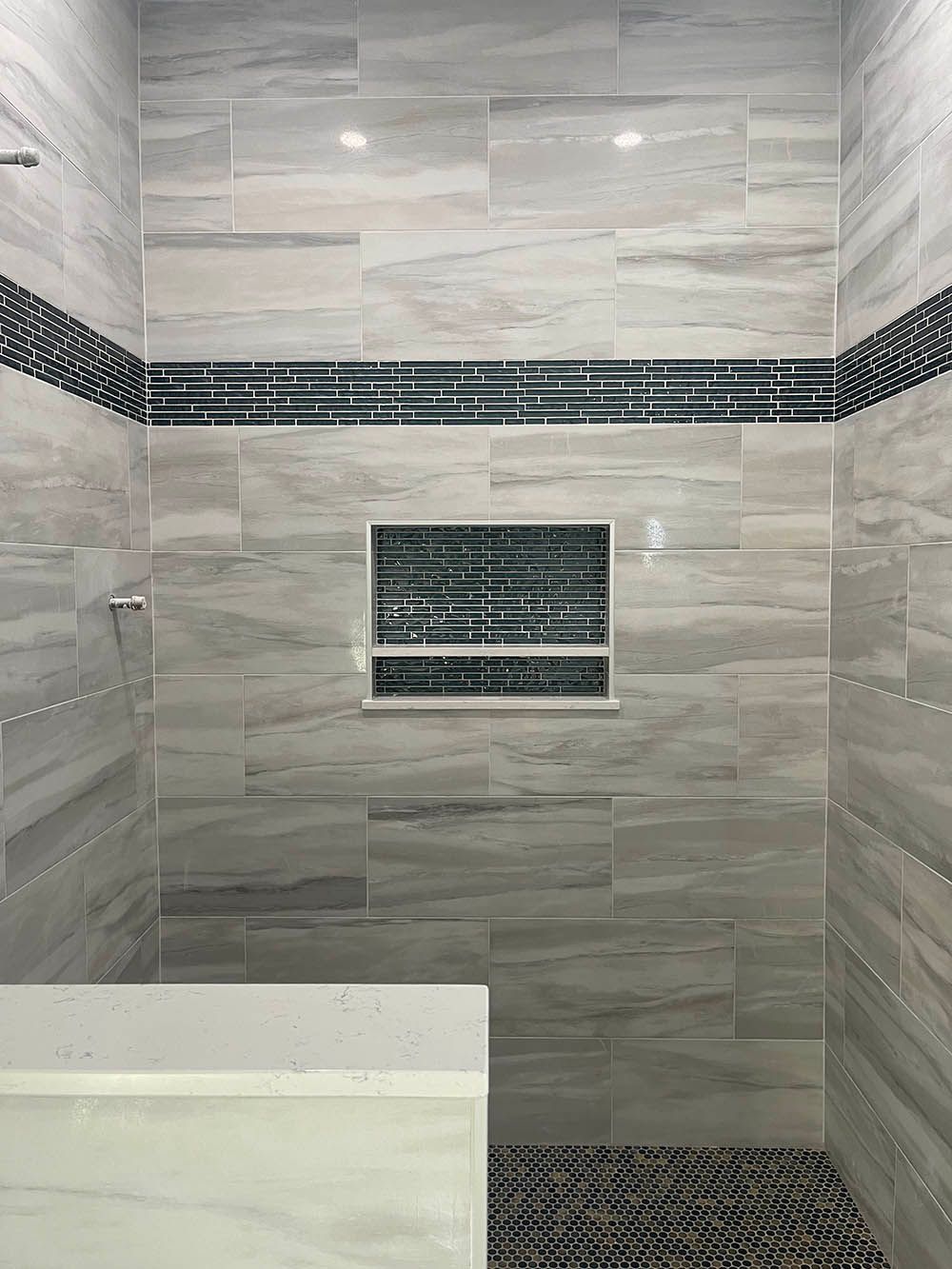 A bathroom with a walk in shower and a bench.