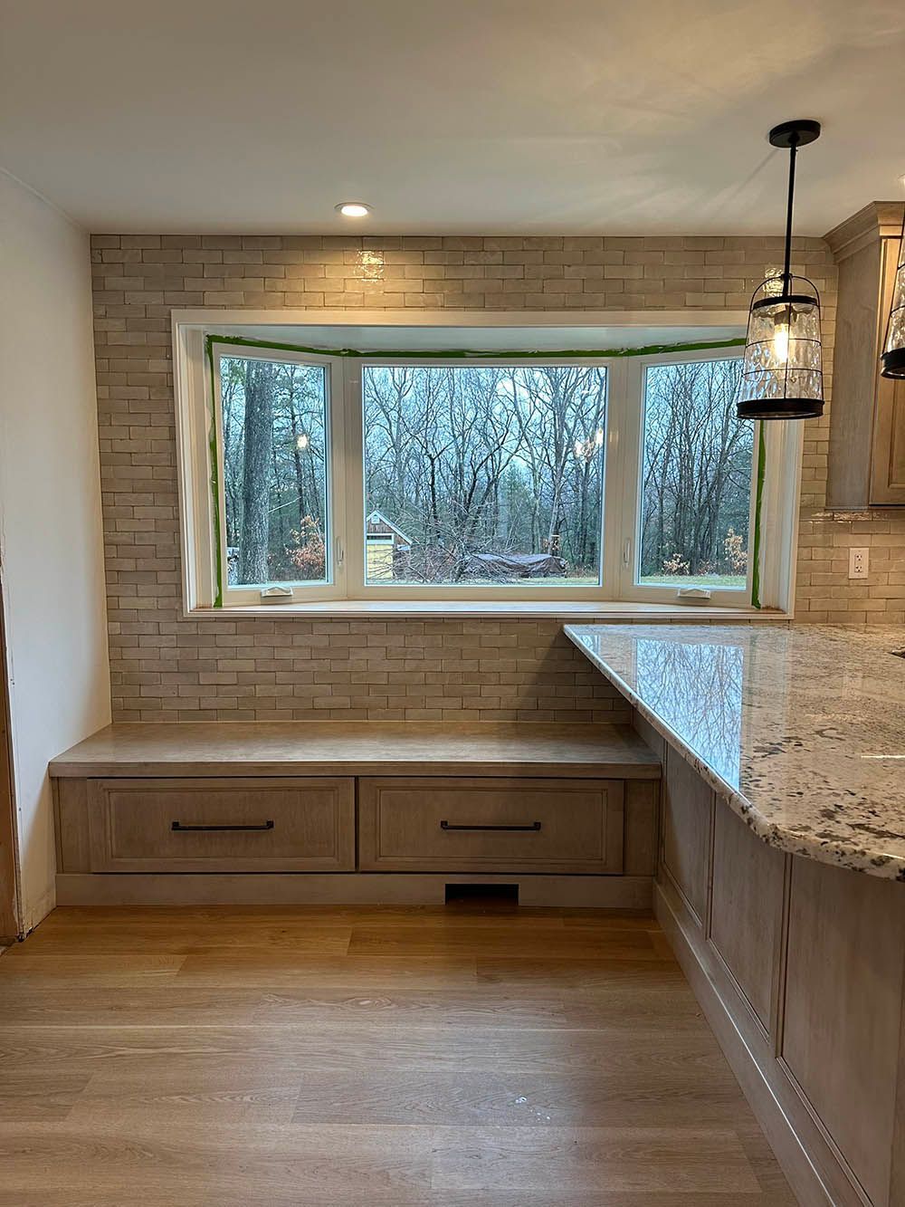 A kitchen with a window seat and drawers underneath it.