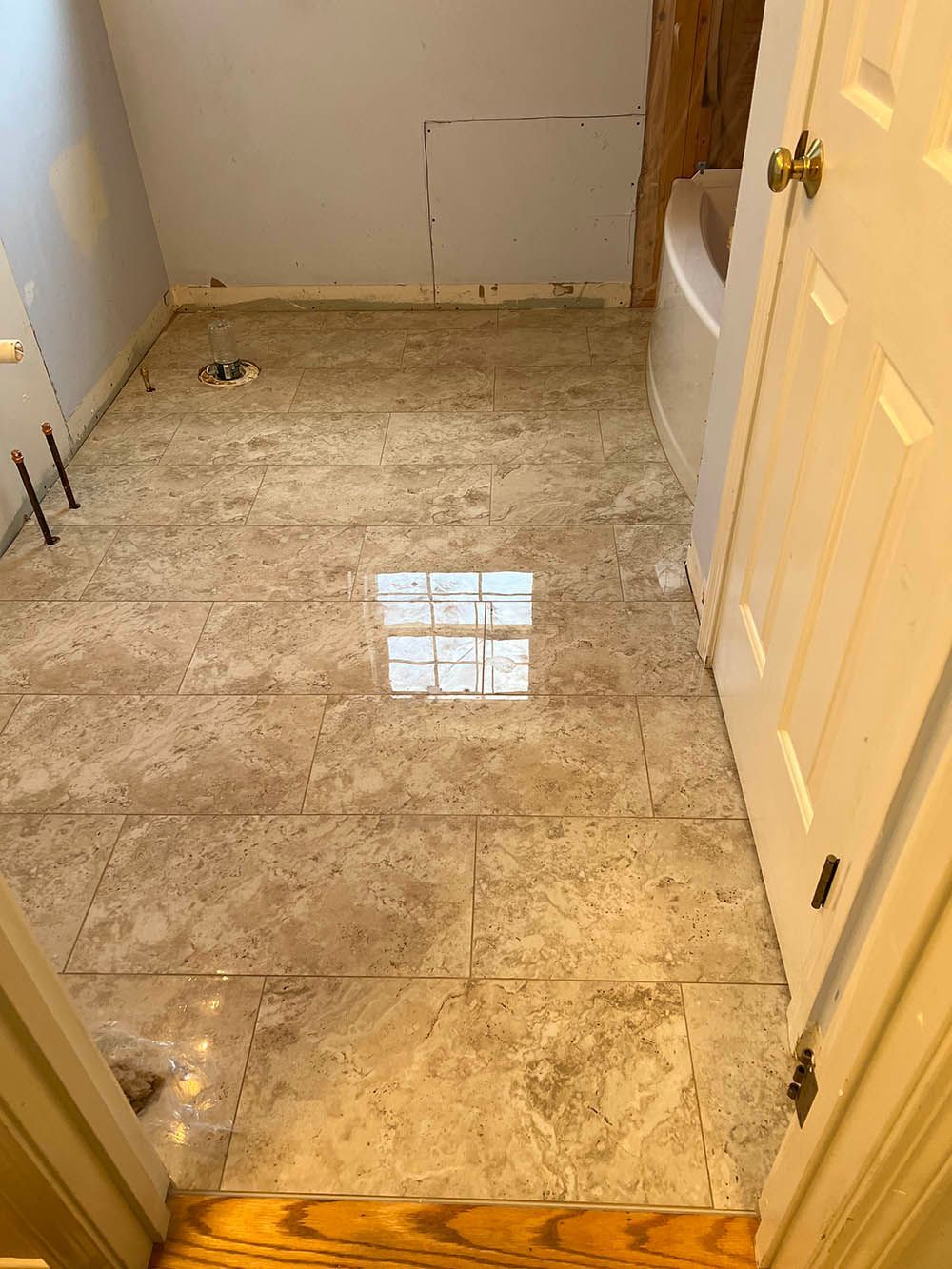 A bathroom with a tiled floor and a bathtub.