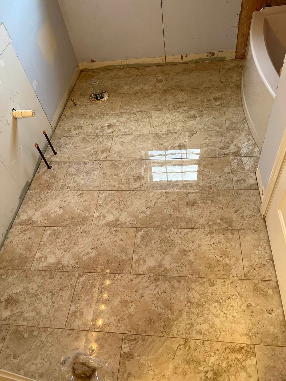 A bathroom with a tiled floor and a bathtub.