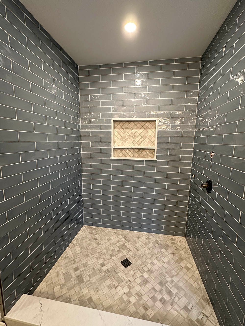 A bathroom with a walk in shower and a brick wall.