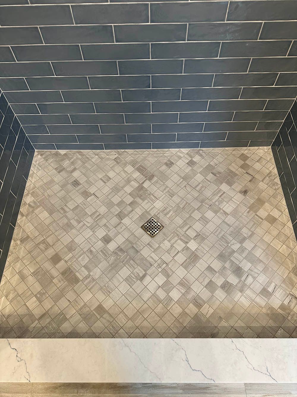 A shower stall with a drain in the middle of it.