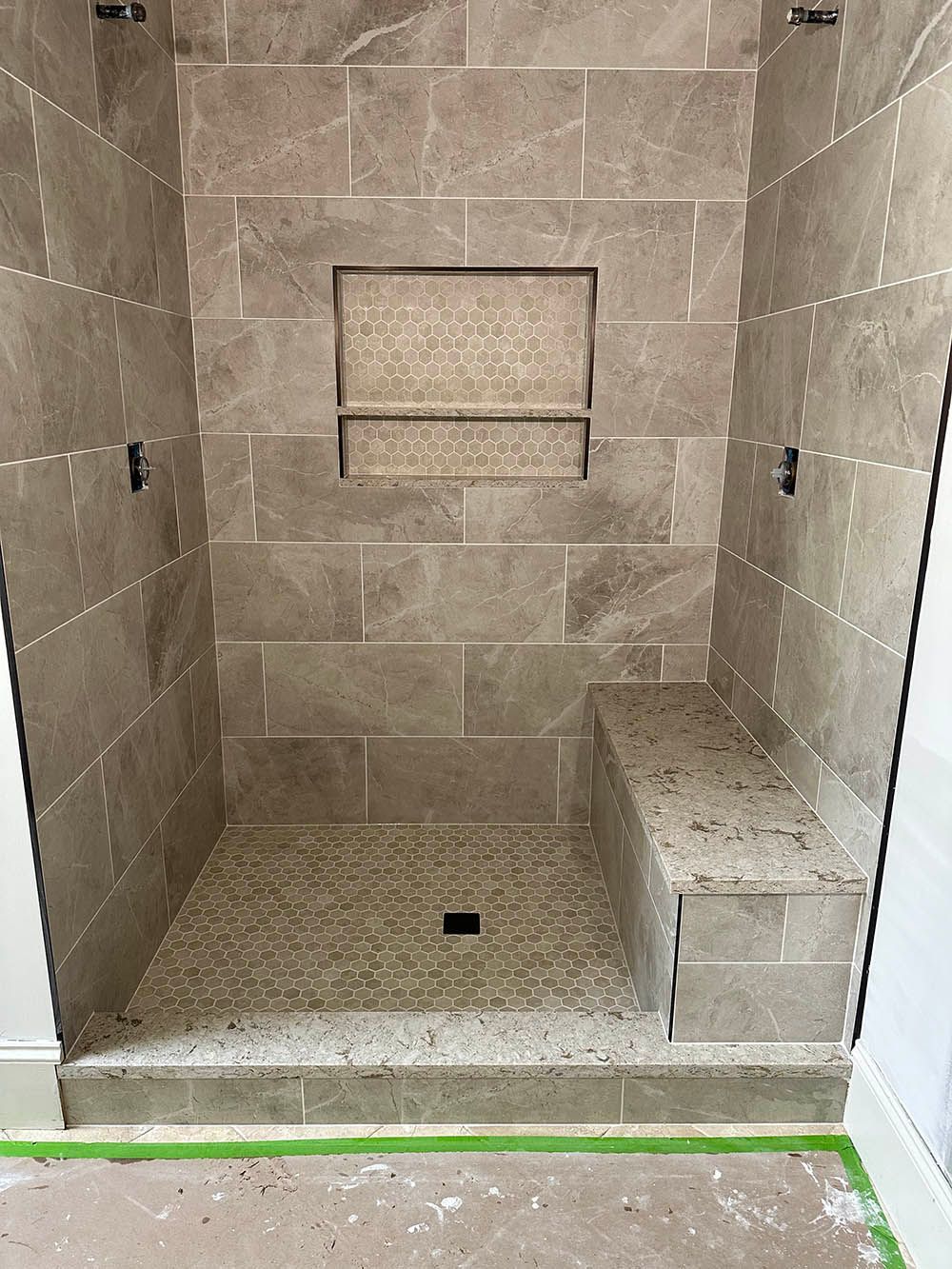 A shower with a bench and a shelf on the wall.