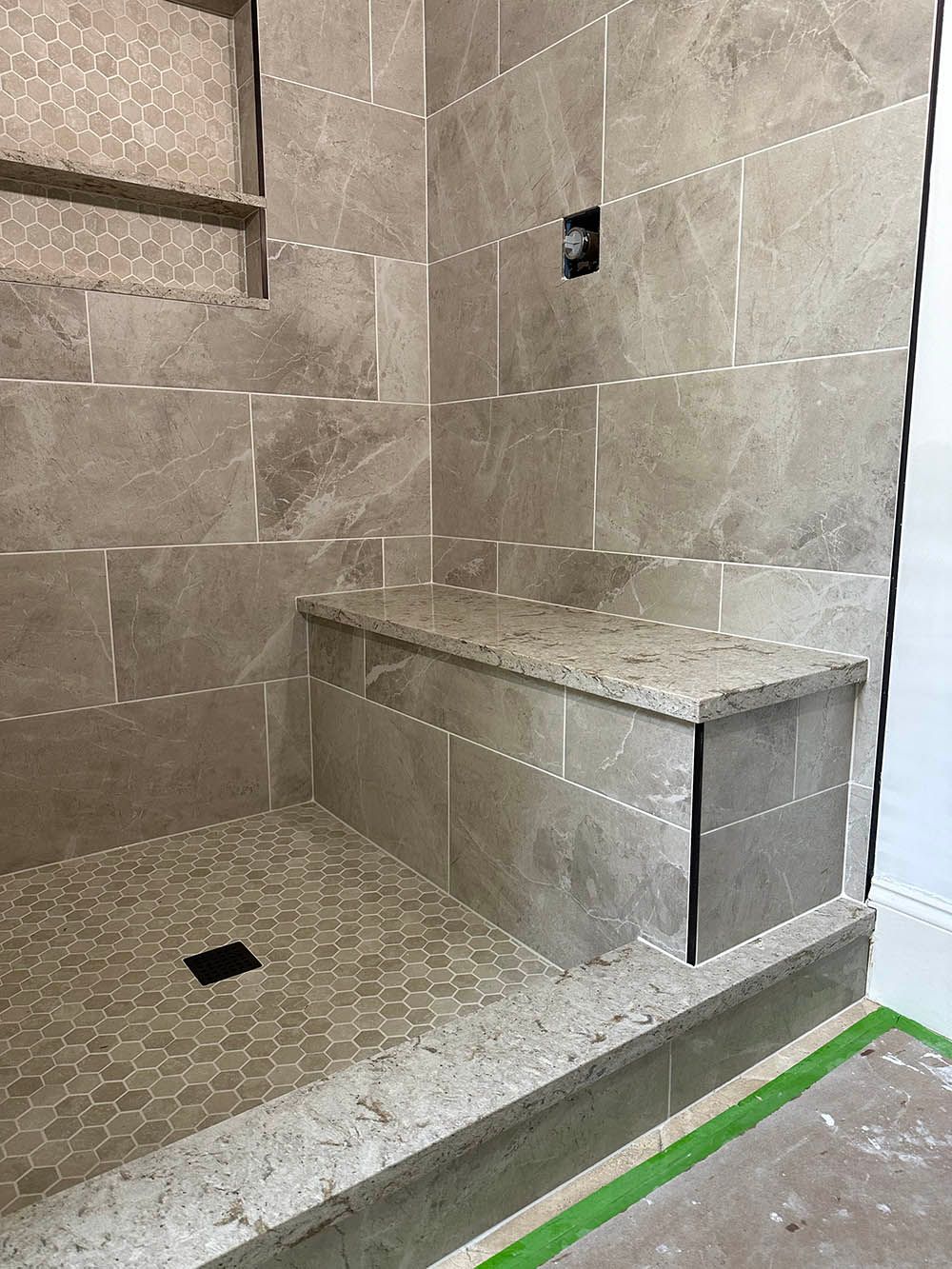 A bathroom with a walk in shower and a bench.