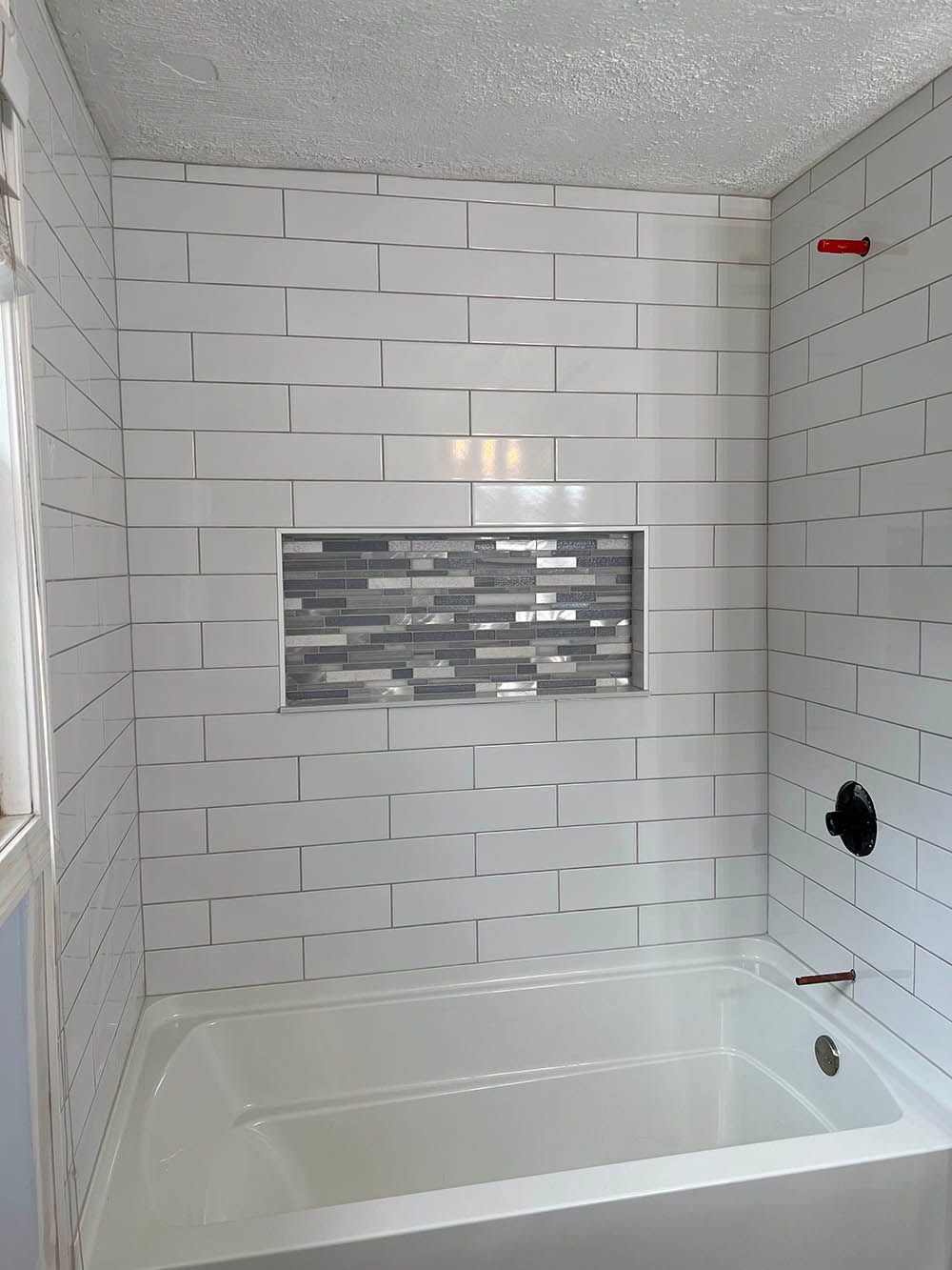 A bathroom with white tiles and a bathtub.