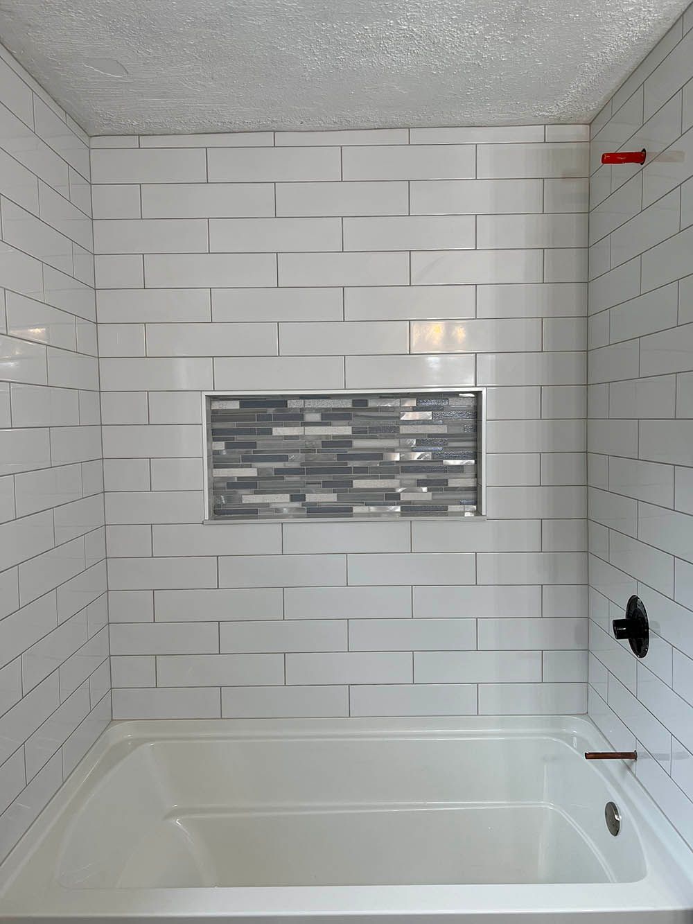 A bathroom with white tile walls and a bathtub.