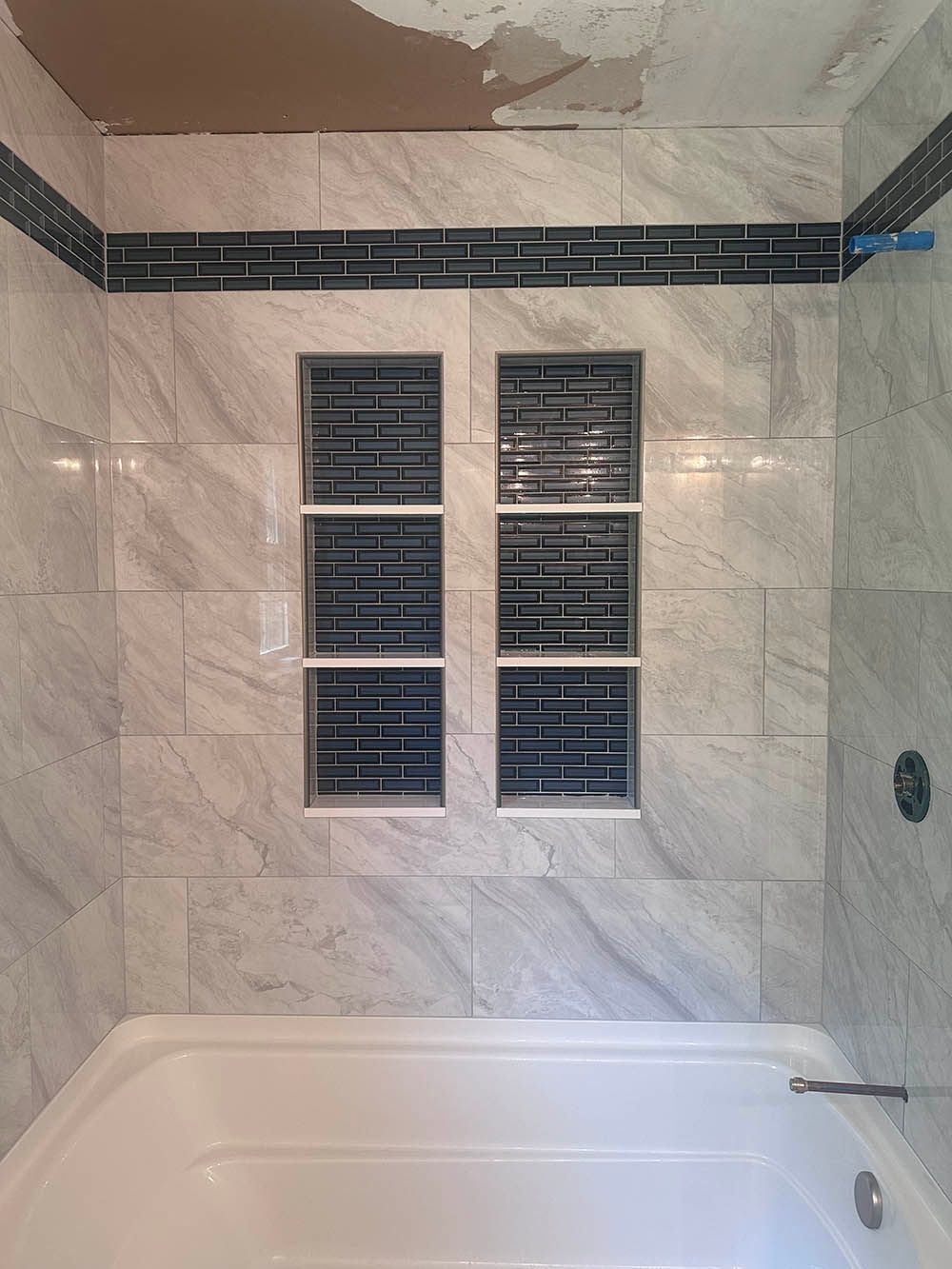 A bathtub in a bathroom with marble tiles and a window.