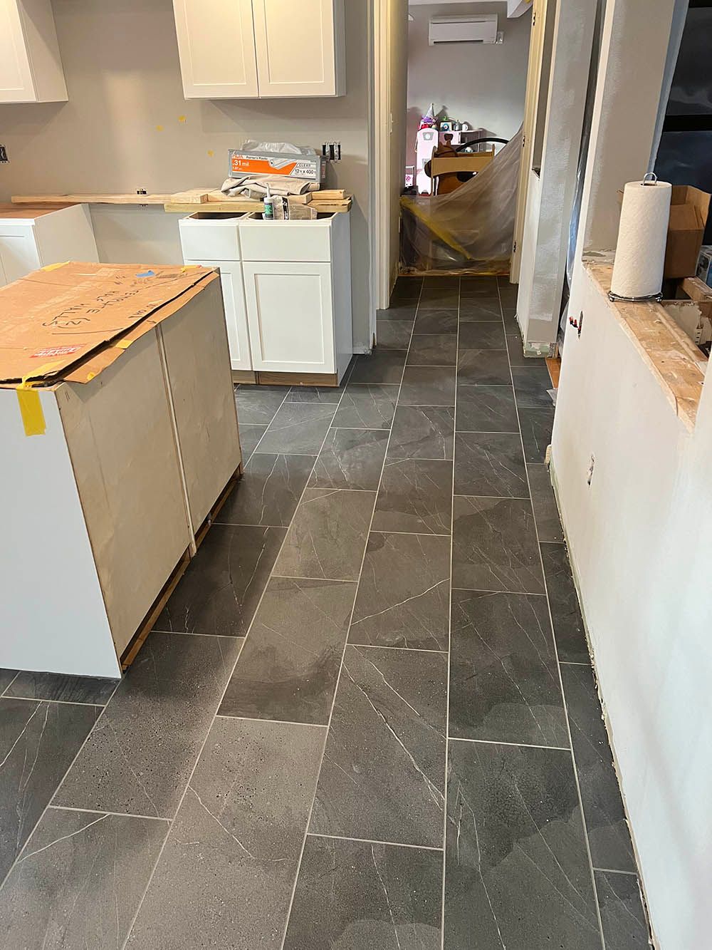 A kitchen under construction with a tiled floor and white cabinets.
