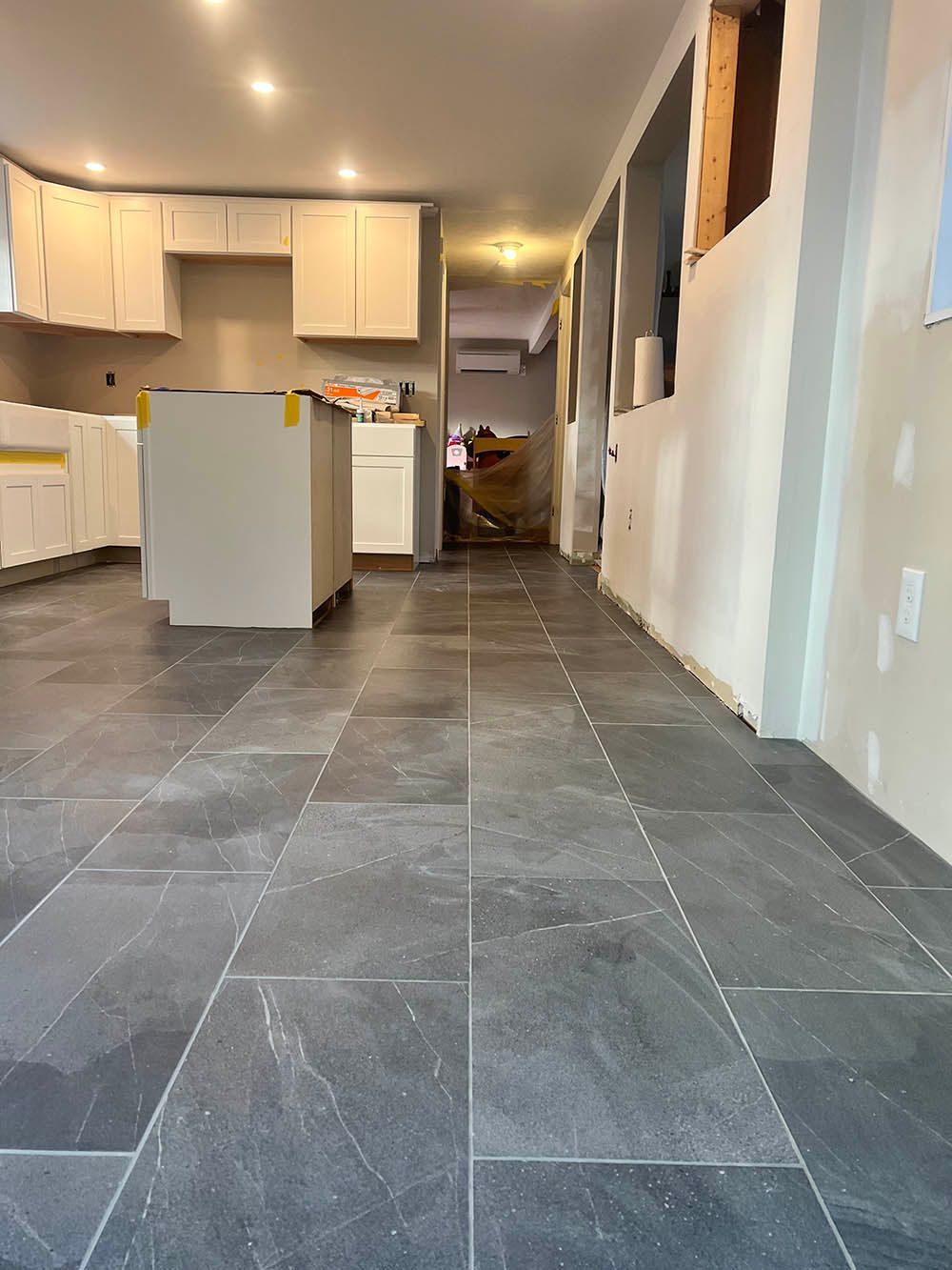 A kitchen under construction with a tiled floor and white cabinets.