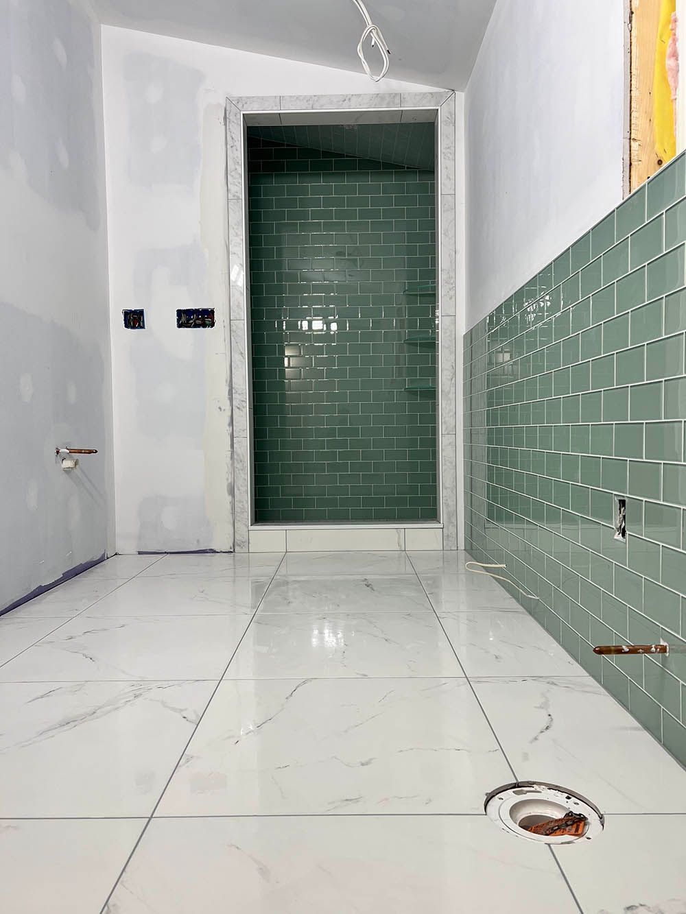 A bathroom under construction with green tiles and white tiles.
